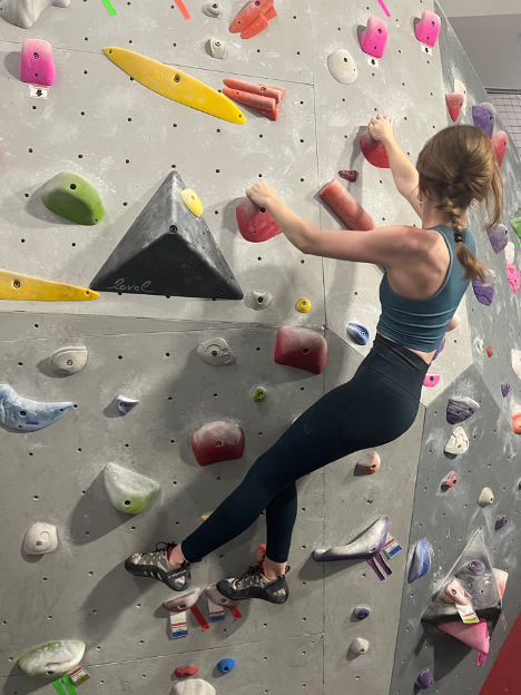 Woman climbing indoor rock wall.