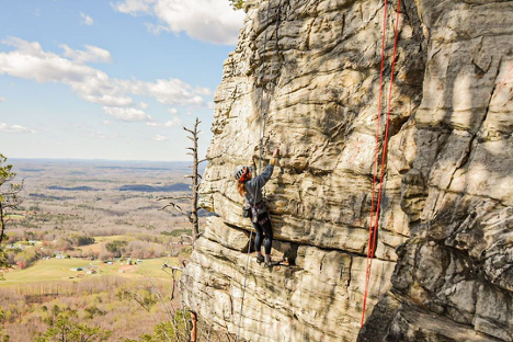 Woman climbing rock face of  a mountain.