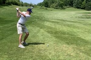Man swinging a golf club on a golf course.