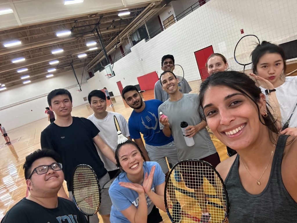 group of 10 students in a gym holding badminton rackets
