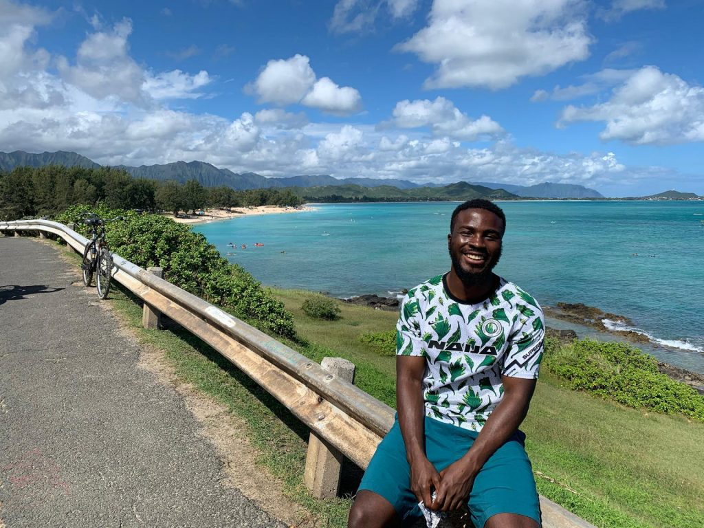 Man sitting on rail by the ocean in Hawaii